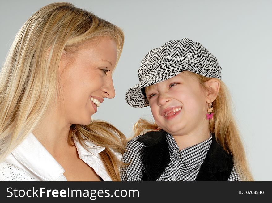 Cute happy blond mother & daughter wearing cap. Cute happy blond mother & daughter wearing cap