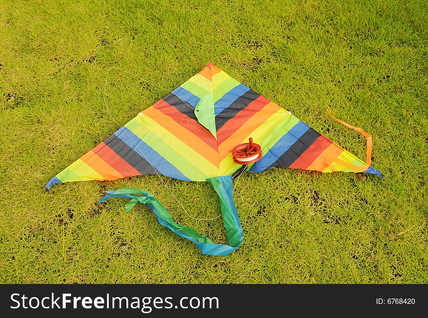 The colorful kite  lying on  the verdure spring meadow. The colorful kite  lying on  the verdure spring meadow.