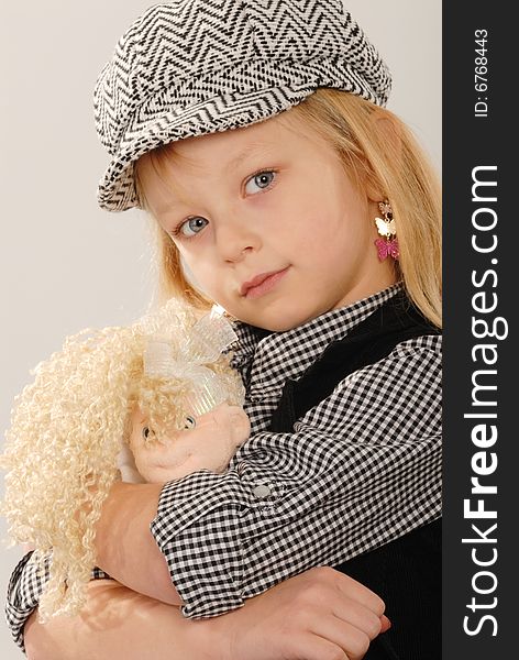 Cute blonde girl in checked cap cuddles doll. Cute blonde girl in checked cap cuddles doll