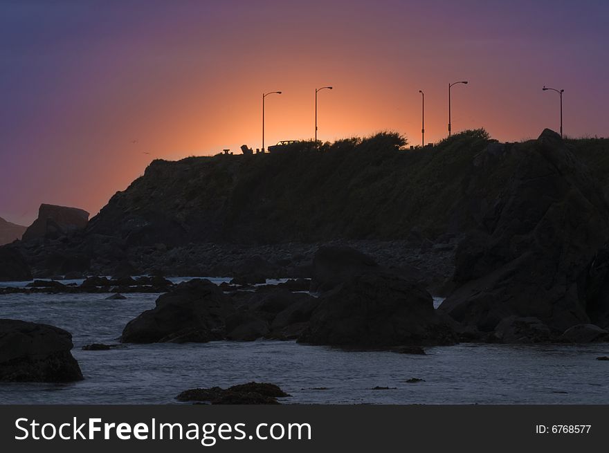 Sunset over California coastline, showing cars parked. Sunset over California coastline, showing cars parked