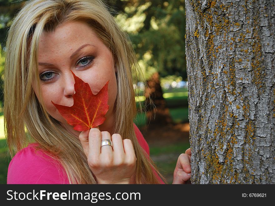A beautiful woman holding a autumn leaf. A beautiful woman holding a autumn leaf