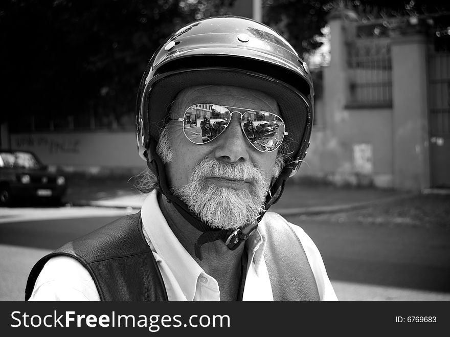 In this shot there is an old man who is riding his motorbike. he wears sun glasses and he has a long beard. In this shot there is an old man who is riding his motorbike. he wears sun glasses and he has a long beard.