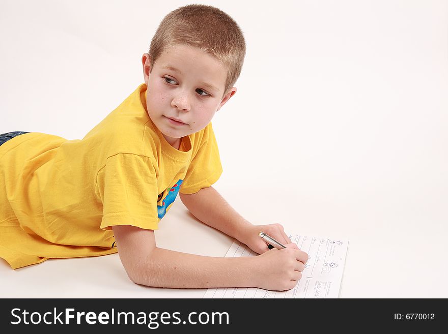 Young boy is writting in his exercise book with pen. Young boy is writting in his exercise book with pen