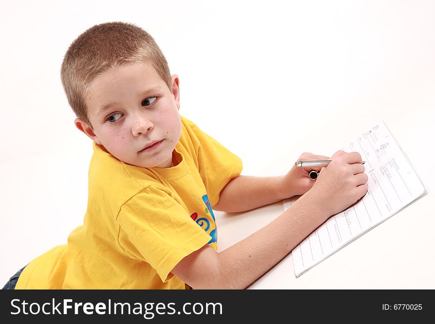 Young boy is writting in his exercise book with pen. Young boy is writting in his exercise book with pen