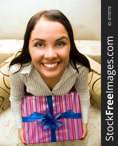 Funny girl holding a gift box with blue bow
