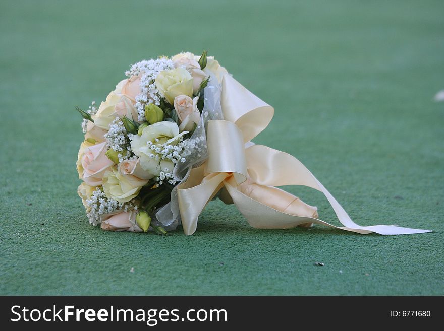 The beautiful wedding bouquet of roses lays on a grass.