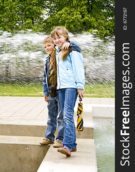 The boy and the girl stand against a fountain. The boy and the girl stand against a fountain