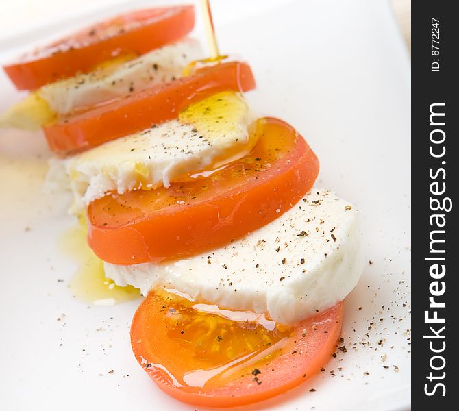 Slices of tomato and mozzarella with pepper and olive oil