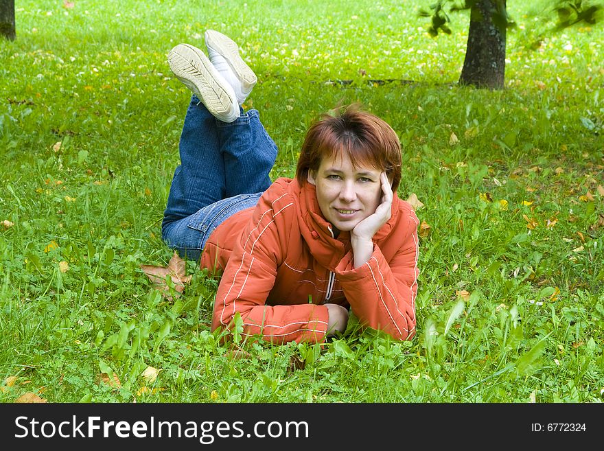 The young woman lays on a grass in park