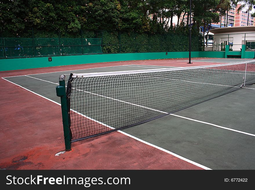 A empty tennis court with trees at background.