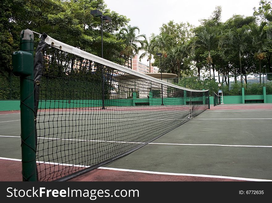 A empty tennis court with trees at background.