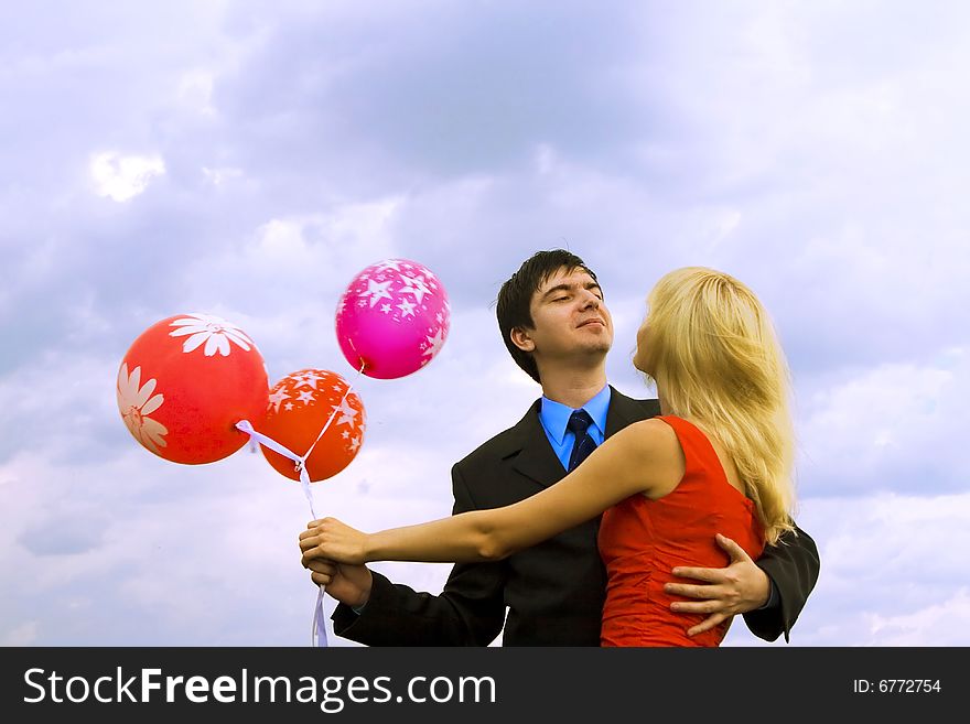 Couple with balloons over sky