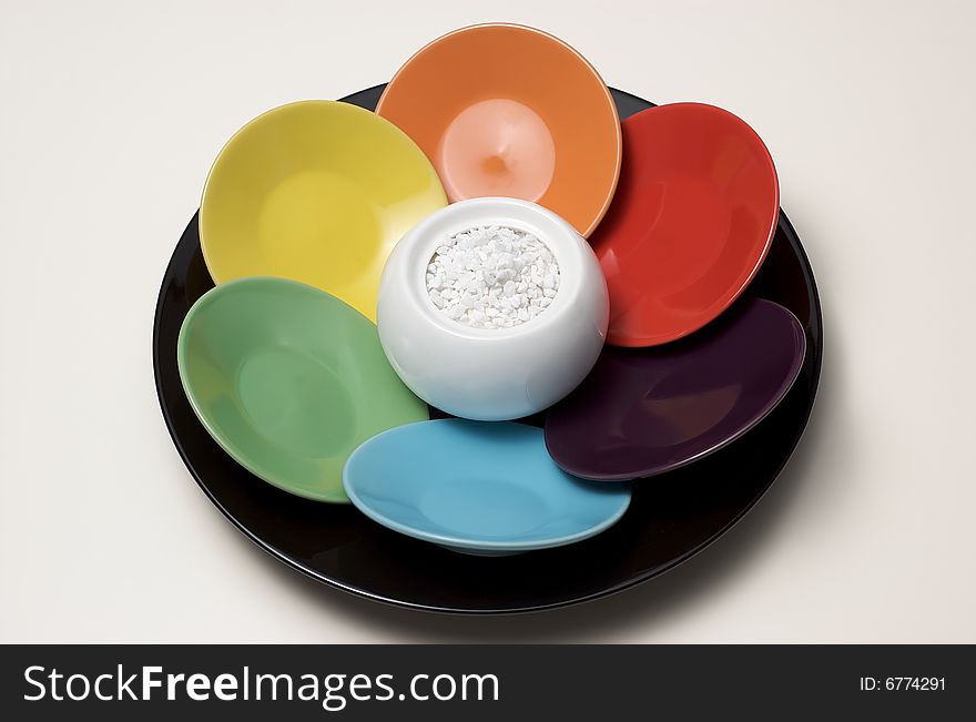 Set of colorful coffee saucers arranged around a sugar cup