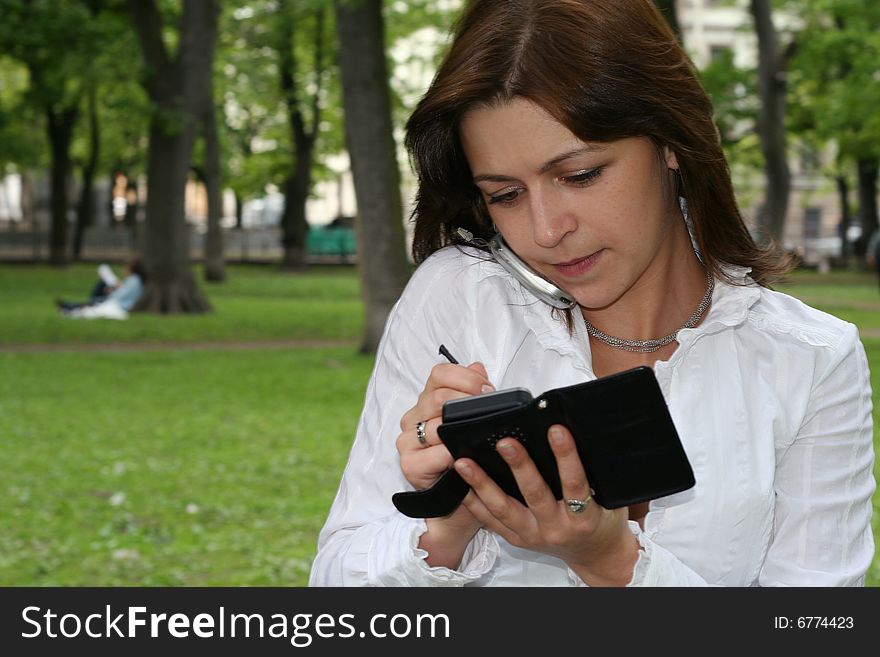 Young woman is talking by mobile phone in a park