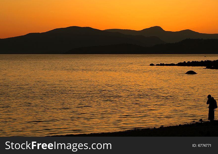 Silhouette of a man standing in a beach looking at a beautiful sunset