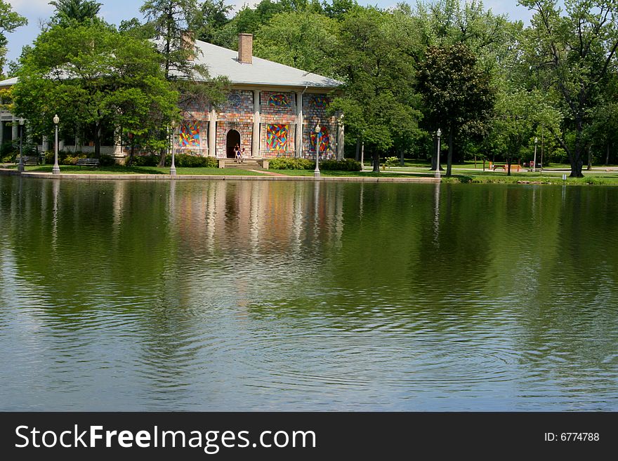 View of building in the park from across a pond which is reflecting the building.