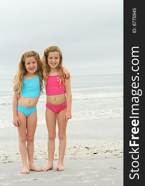 Shot of twin sisters at the beach vertical