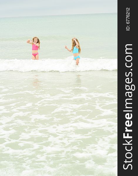 Shot of twin sisters running from the waves vertical