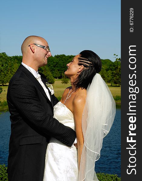 Bride and groom are standing close together looking at each other.