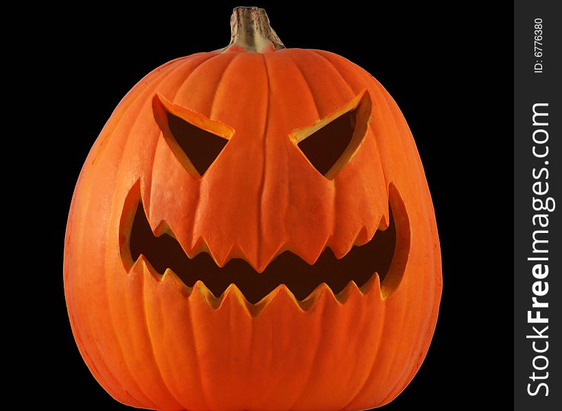 A lone jack-o-lantern with black eyes and mouth grins maniacally on a pitch black Halloween night. A lone jack-o-lantern with black eyes and mouth grins maniacally on a pitch black Halloween night.