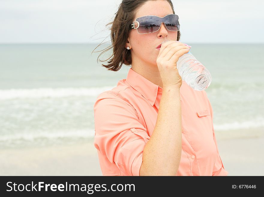 Beautiful Brunette Drinking Water At The Beach