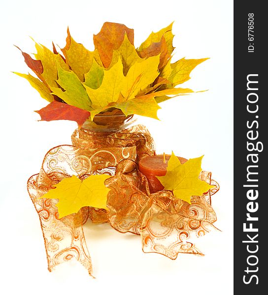 Bright maple leafs arranged in a glass vase with ribbon and candle. Bright maple leafs arranged in a glass vase with ribbon and candle