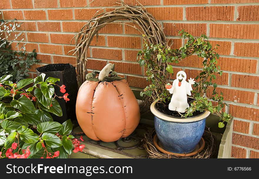 A ghost and pumpkin adorn potted plants. A ghost and pumpkin adorn potted plants.