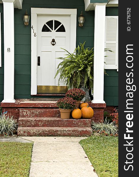 A welcoming entryway with a boston fern, mums and a pumpkin. A welcoming entryway with a boston fern, mums and a pumpkin.