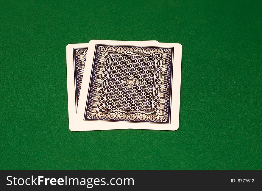 Two cards with faces down on the green table. Two cards with faces down on the green table