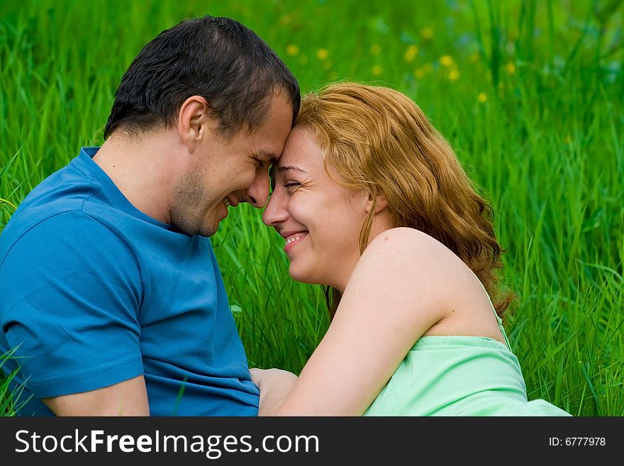 Portrait of a young loving couple laughing in grass. Portrait of a young loving couple laughing in grass