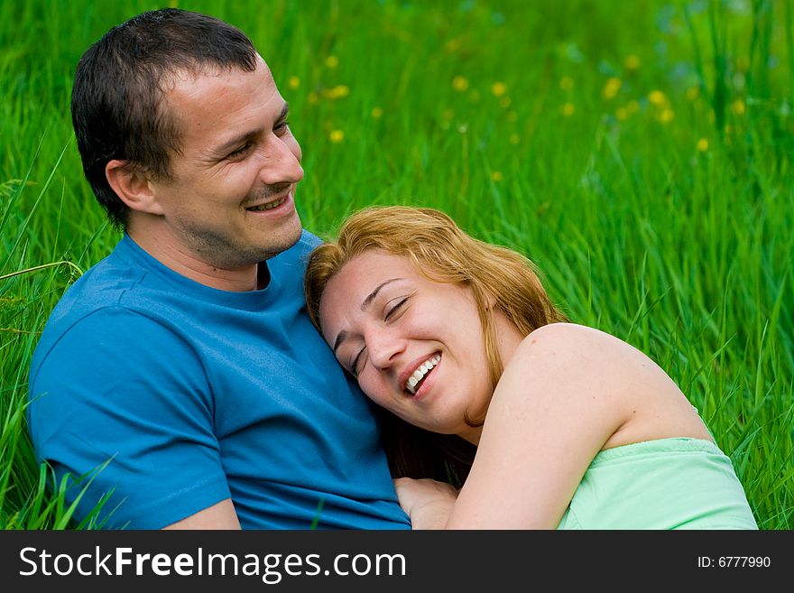 Portrait of a young loving couple laughing in grass. Portrait of a young loving couple laughing in grass