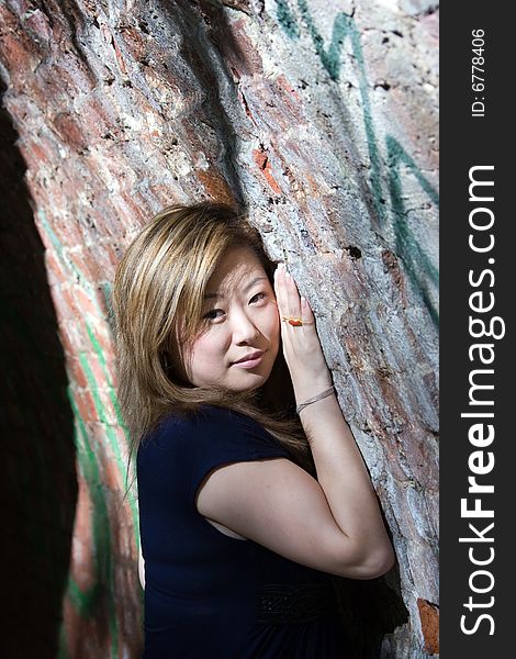 Beautiful asian woman snuggle up to brick wall