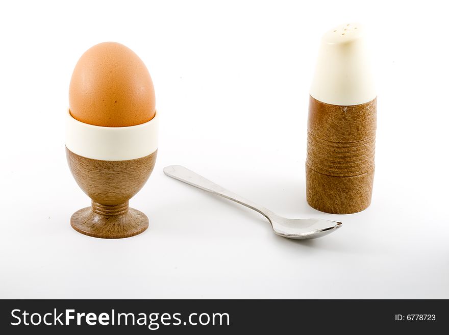 A soft boiled egg, a teaspoon and a saltpot