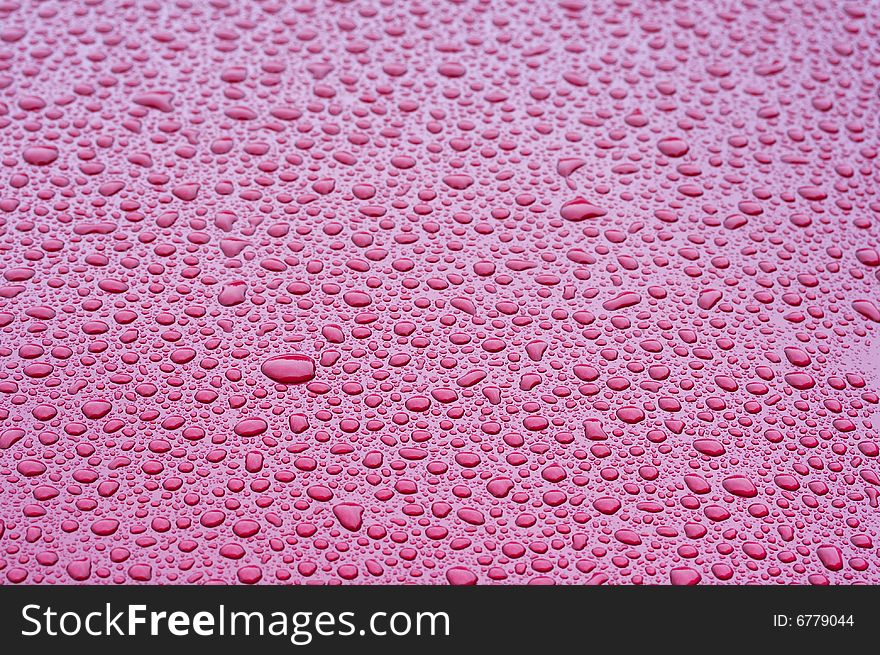 A picture of water drops on a red metal surface. A picture of water drops on a red metal surface