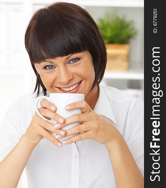 Beautiful business woman holding cup of coffee in her office