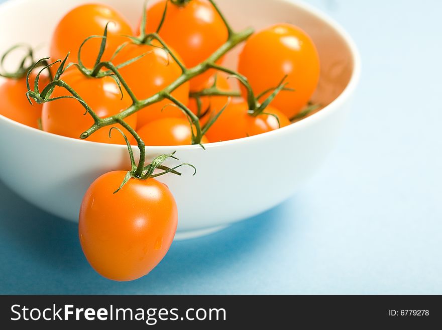 Fresh cherry tomatoes on the vine in white porcelain bowl. Fresh cherry tomatoes on the vine in white porcelain bowl