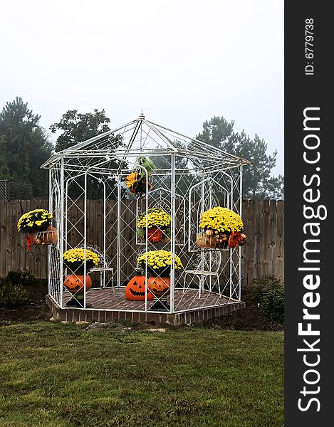 A White gazebo decorated for fall with mums, pumpkins and flowers. A White gazebo decorated for fall with mums, pumpkins and flowers