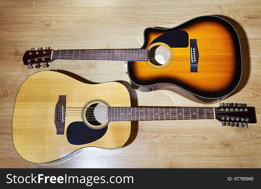 Two acoustic guitars lying on wooden floor closeup
