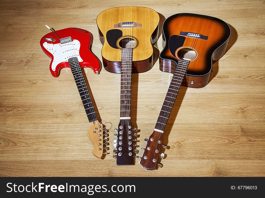 Two acoustic and one electric guitars lying on wooden floor. Two acoustic and one electric guitars lying on wooden floor