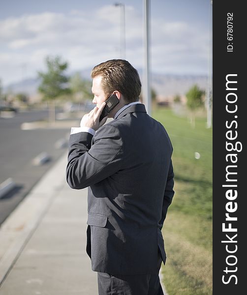 Businessman talking on his cell phone about business while standing outside in his business suit. Businessman talking on his cell phone about business while standing outside in his business suit