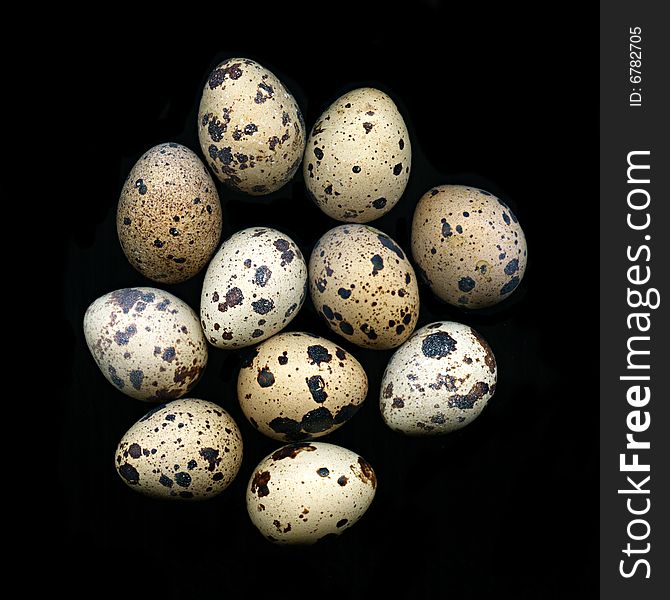 A pile of quail eggs against black background