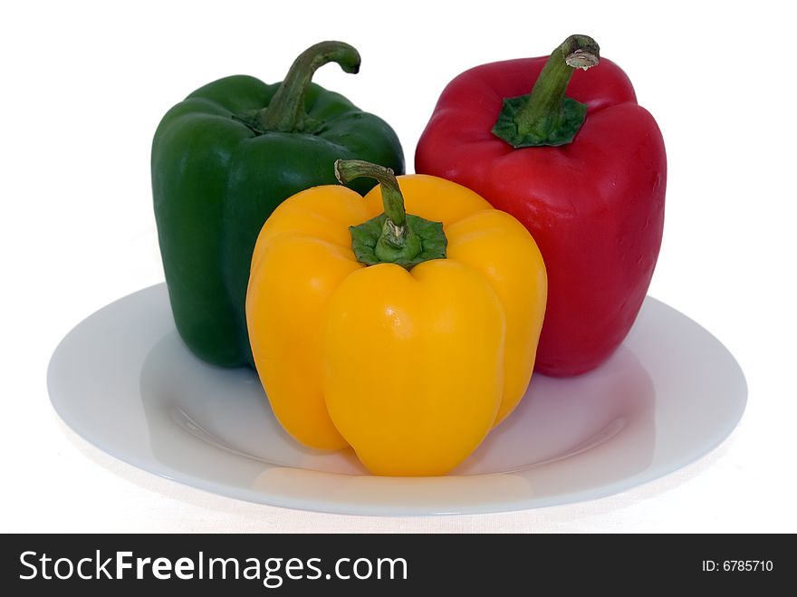 Three coloured paprikas on white plate separated on white background. Three coloured paprikas on white plate separated on white background