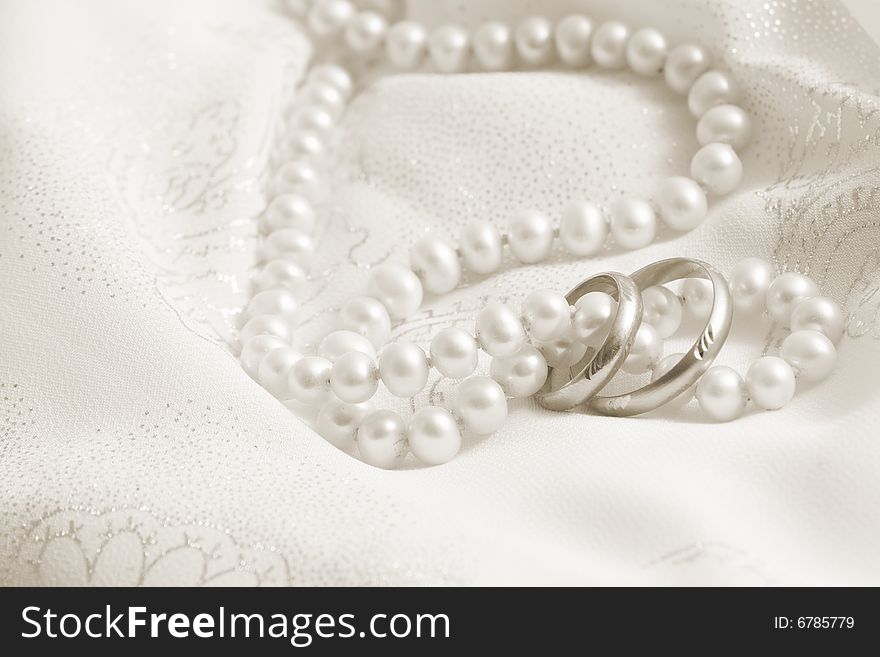 Wedding background: pearls and rings on a fabric. Toning in sepia. Wedding background: pearls and rings on a fabric. Toning in sepia.
