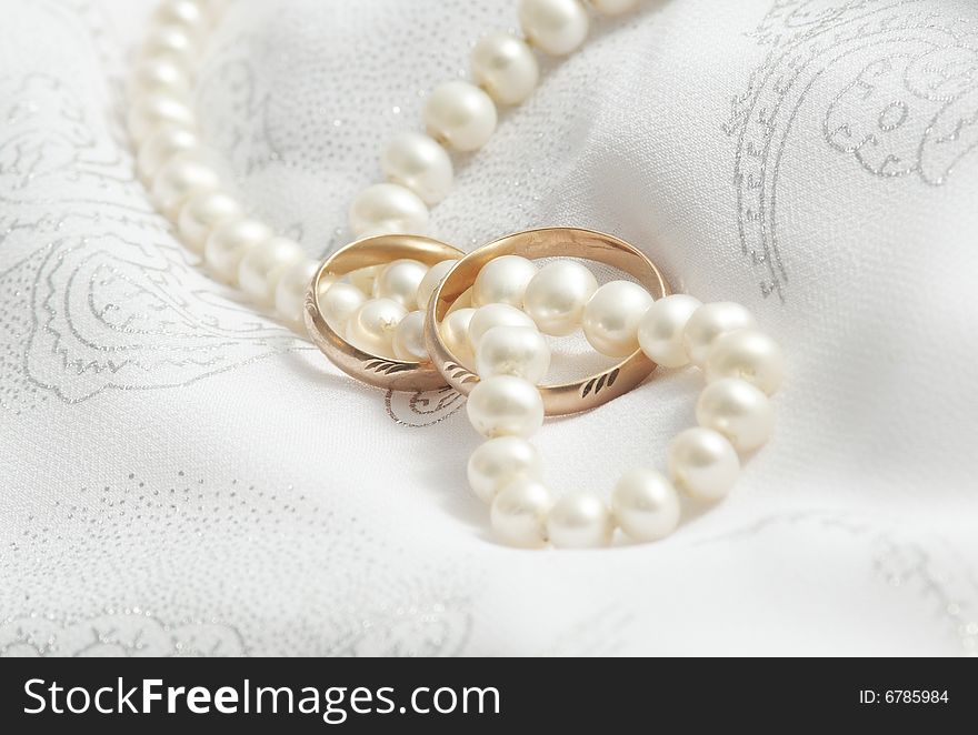 Pearls and wedding bangs on a fabric.