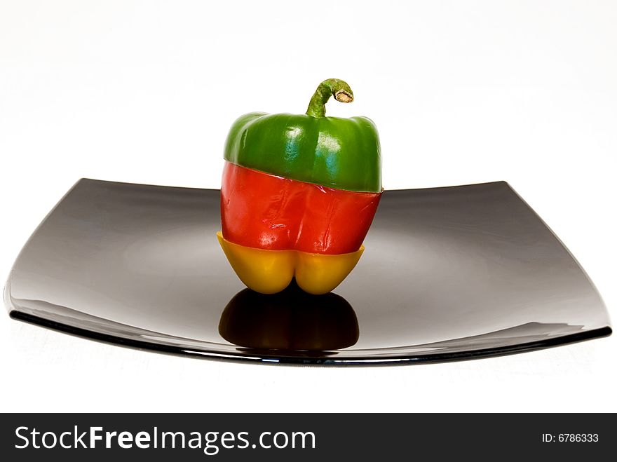 Tricolor paprika on black plate separated on white background