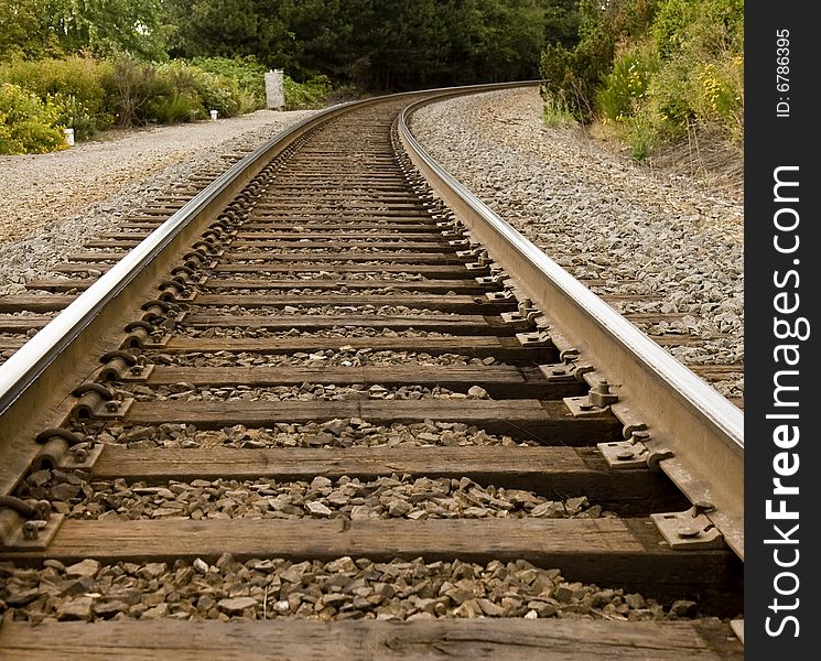 Train tracks disappearing around a curve in the trees. Train tracks disappearing around a curve in the trees