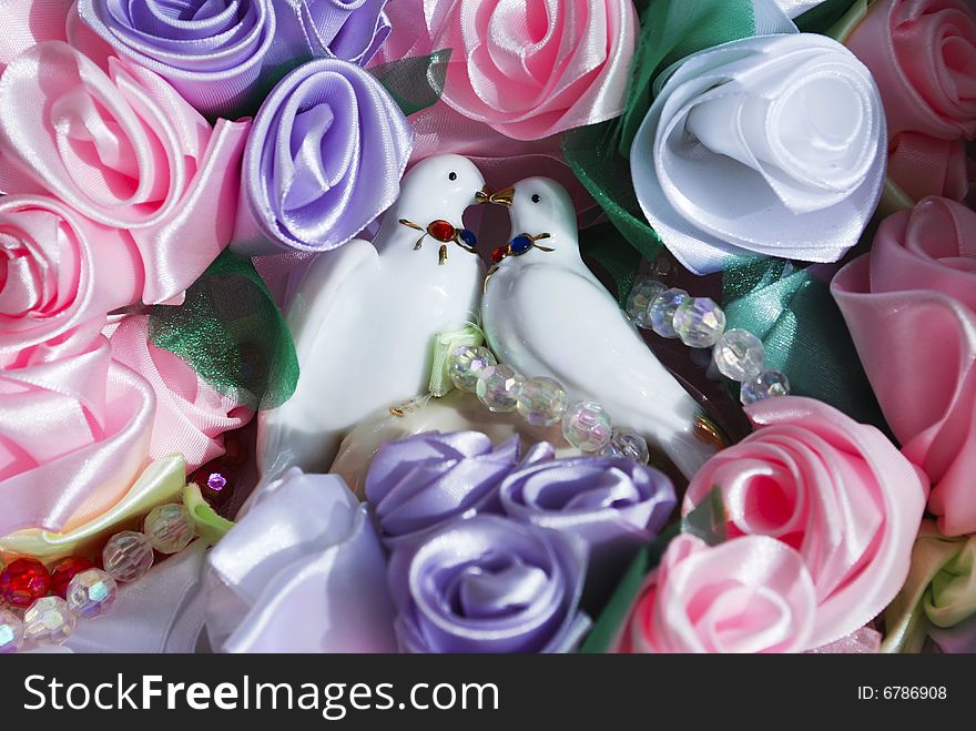 Porcelain figurine of  dove couple surrounding with silk flowers. Porcelain figurine of  dove couple surrounding with silk flowers.