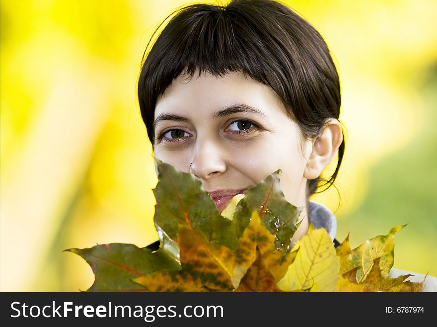 Young woman with maple leaves in hand