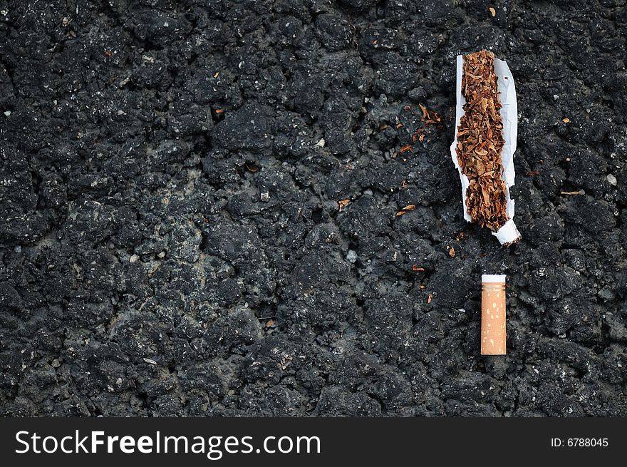 Torn apart cigarette on bitumen surface. Torn apart cigarette on bitumen surface