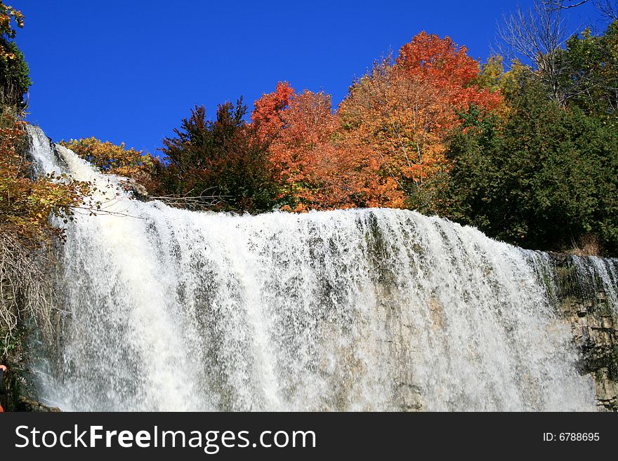 Streams of waterfall among the colored autumn trees. Streams of waterfall among the colored autumn trees